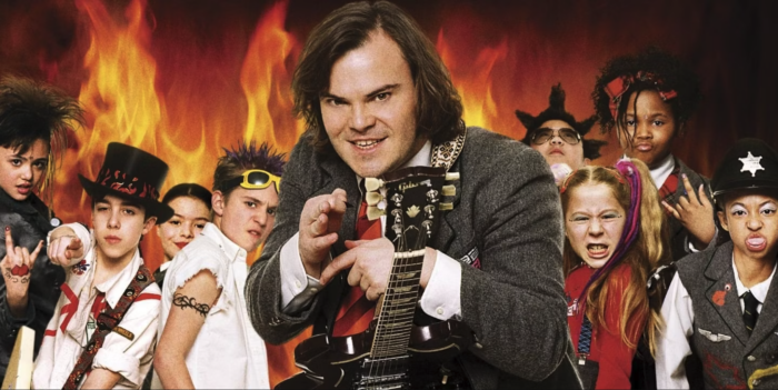 Photo of Jack Black in the middle surrounded by kids in rocker clothes. Images of flames are behind them.