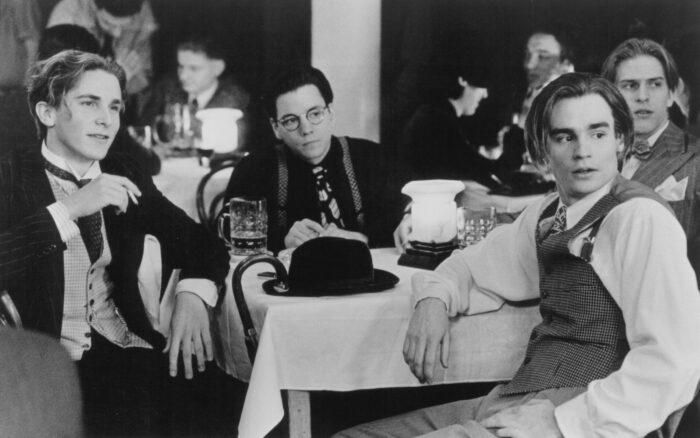 Black and white film still of a group of men sitting at a table
