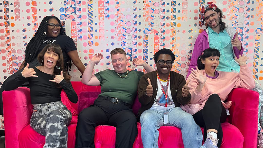 Group of smiling people on a pink couch