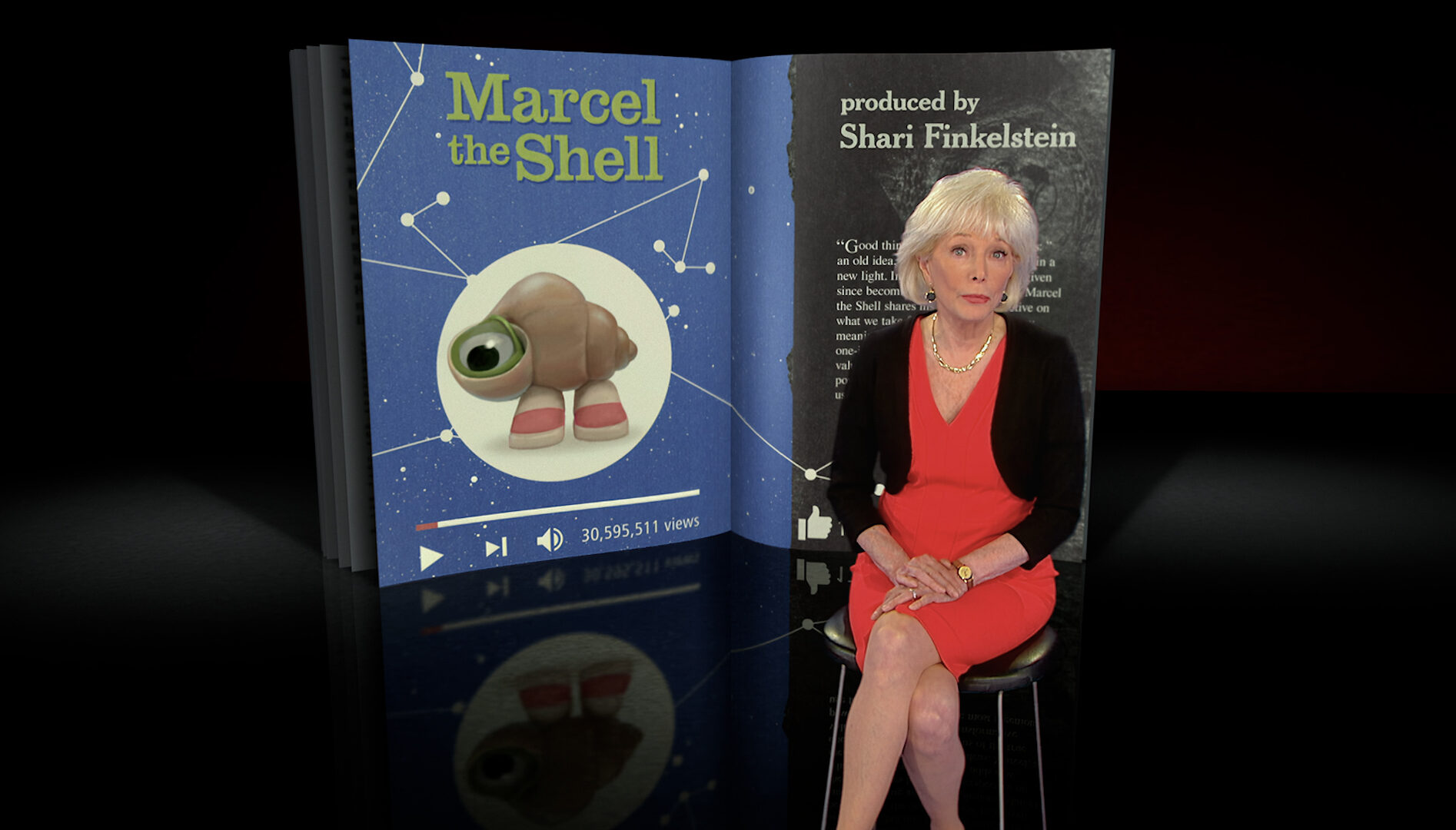 A film still of 60 Minutes host Leslie Stahl sitting in front of a screen that says Marcel the Shell on it with an image of a one-eyed shell wearing sneakers.