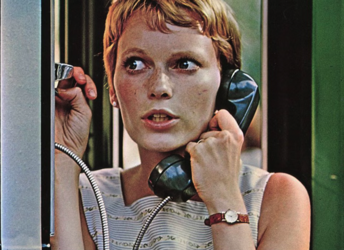 Film still of a scared-looking woman with short blond hair talking on a payphone.
