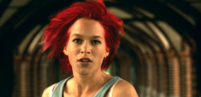 Film still of a woman with red hair running towards the camera.