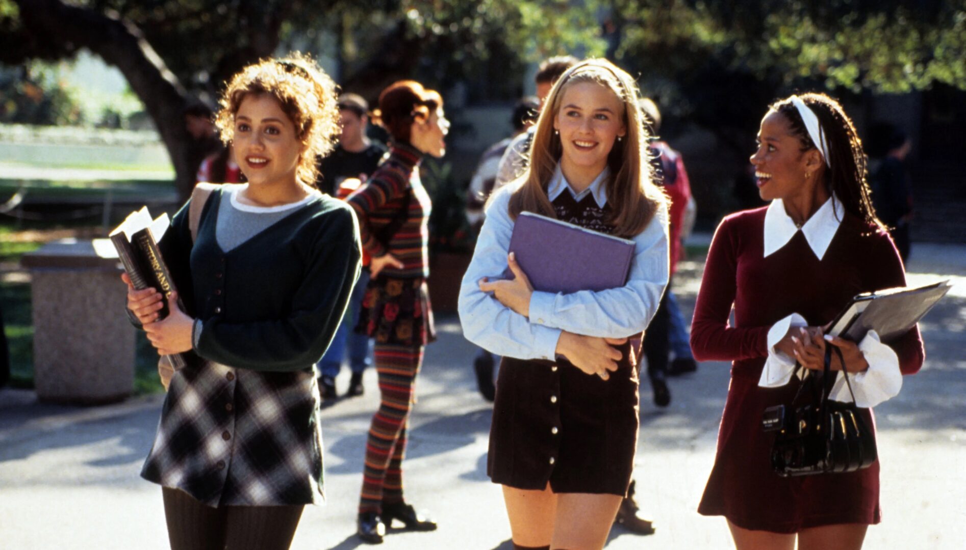 Film still of three high school girls walking outside and holding books