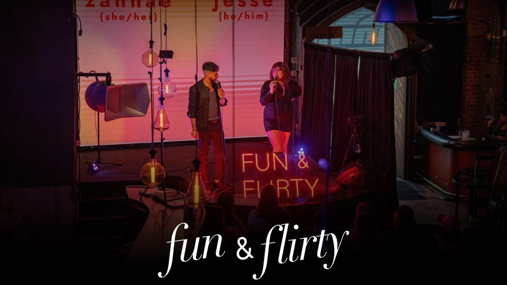 Photo of two people on stage in a darkly lit room, with the words "fun & flirty" over the bottom of the image