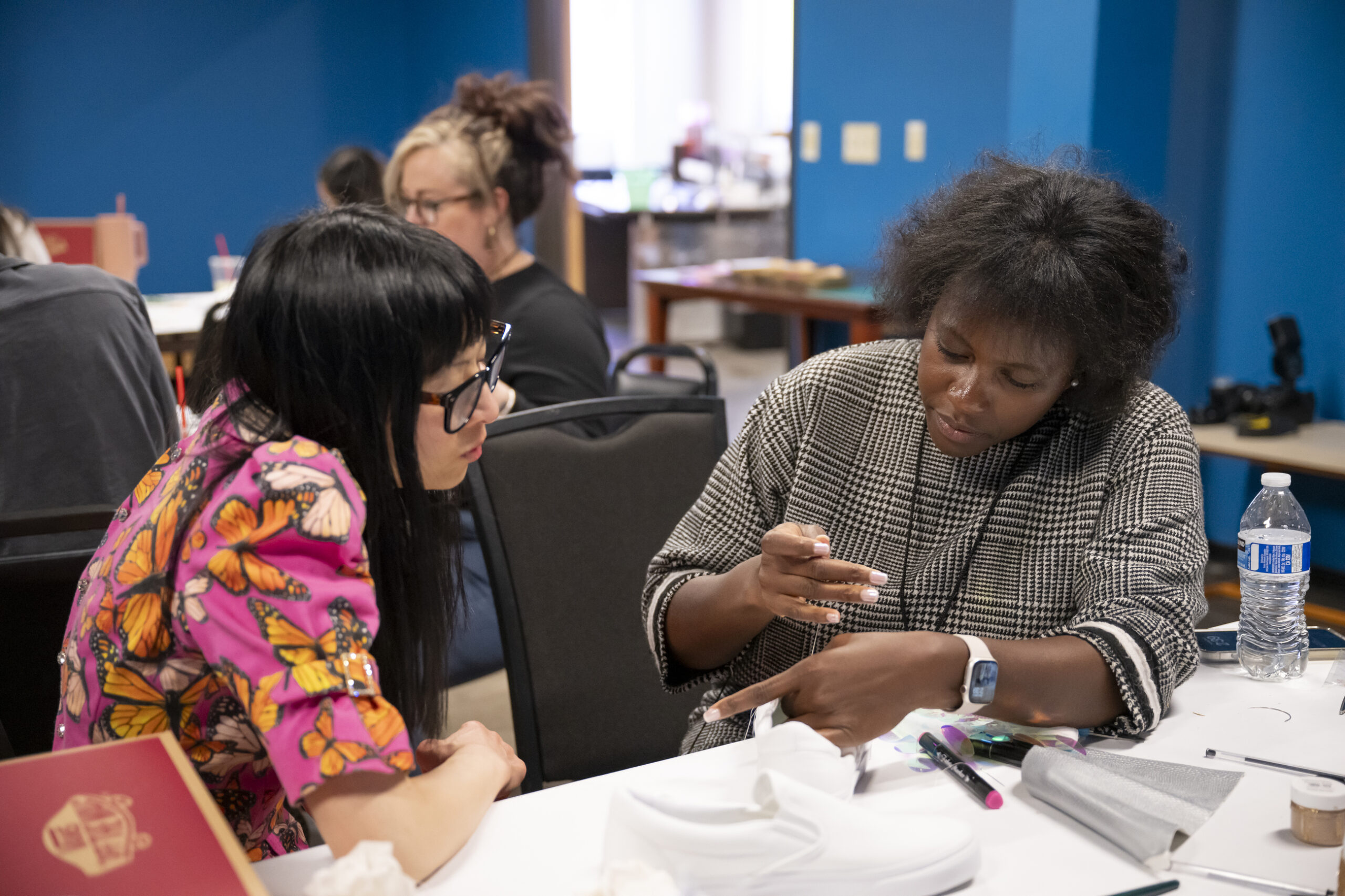 Two women sitting at a table working on a craft together