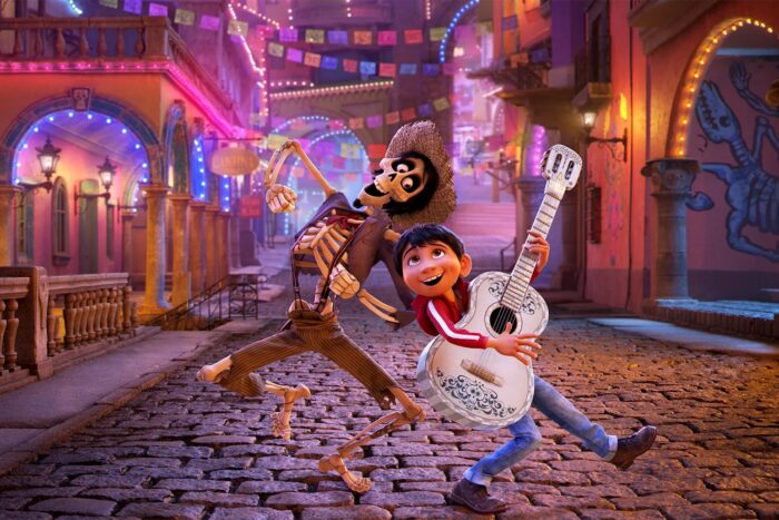 Animated film still of a young boy with a white guitar dancing and singing with a skeleton