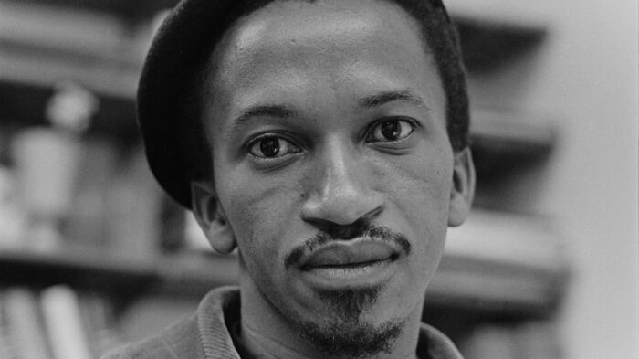 Black and white portrait of a Black man's face. He has a mustache and a beret on.