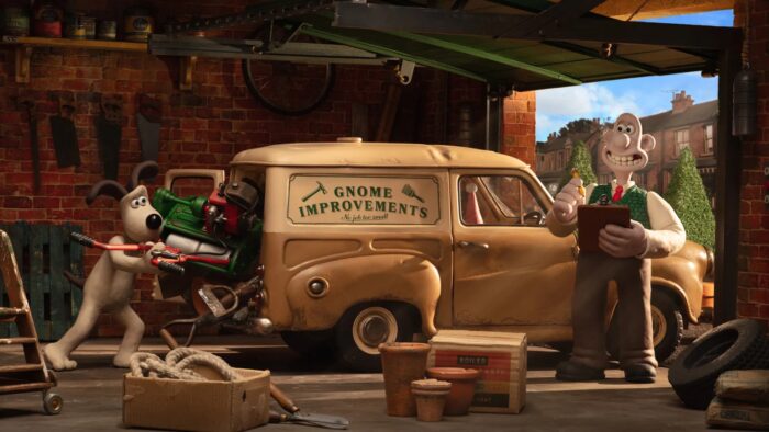 Animation still of a smiling man, holding a clipboard and a pencil, standing in a garage with an old fashioned car and a dog stuffing tools in the trunk of the car