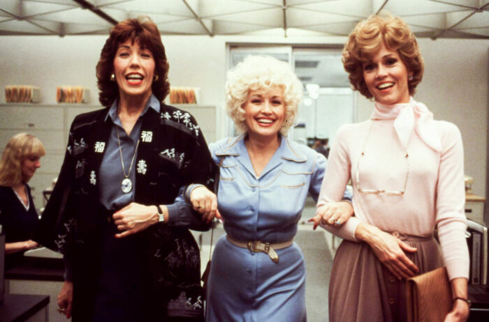 NINE TO FIVE film still with Lily Tomlin, Dolly Parton, and Jane Fonda linking arms