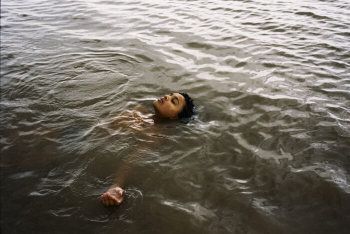 A film still of a child floating on their back in the water