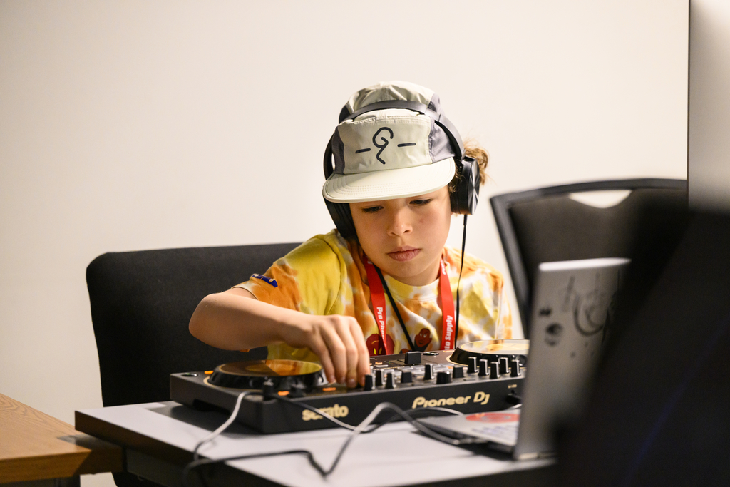 Photo of a boy wearing headphones and working at a mixing console