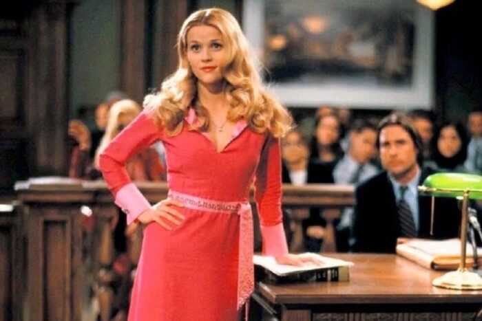 A woman with long blonde hair and a pink dress standing in a courtroom