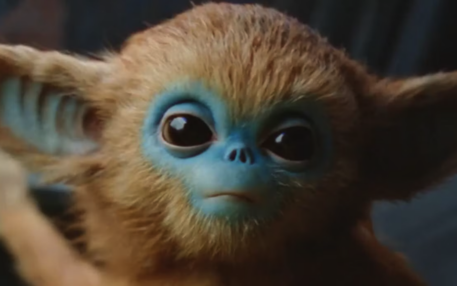 Close up of a fictional creature with fuzzy big ears and face and blue skin around its eyes, nose, and mouth