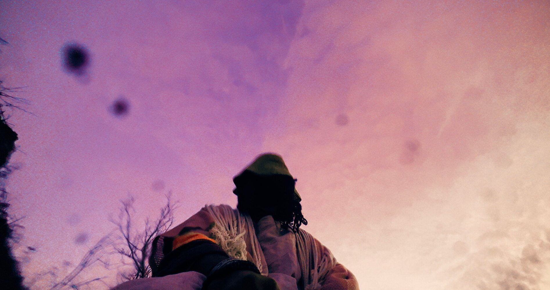 Film still looking up at a seated person against a purplish sky