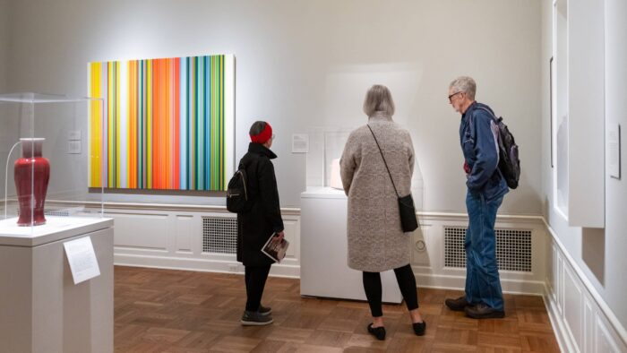 Three people standing around a sculpture in a museum gallery.