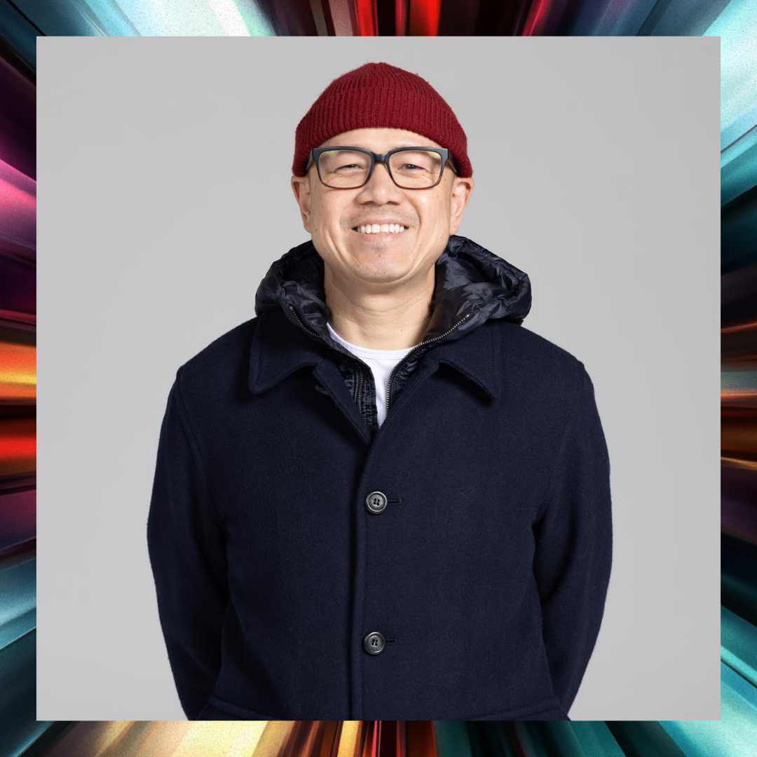 Portrait of a smiling man with eyeglasses and a maroon beanie on