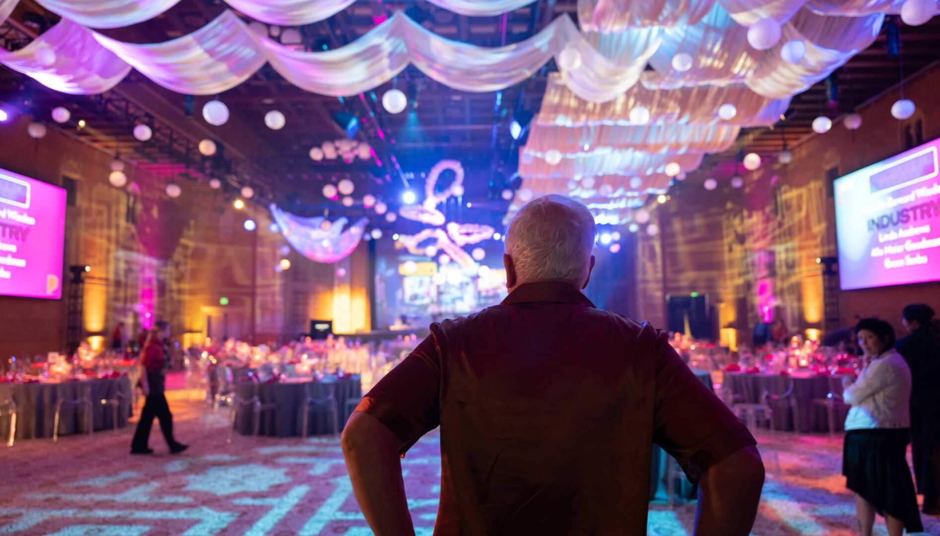 A person standing in an colorful and elaborately decorated banquet hall.