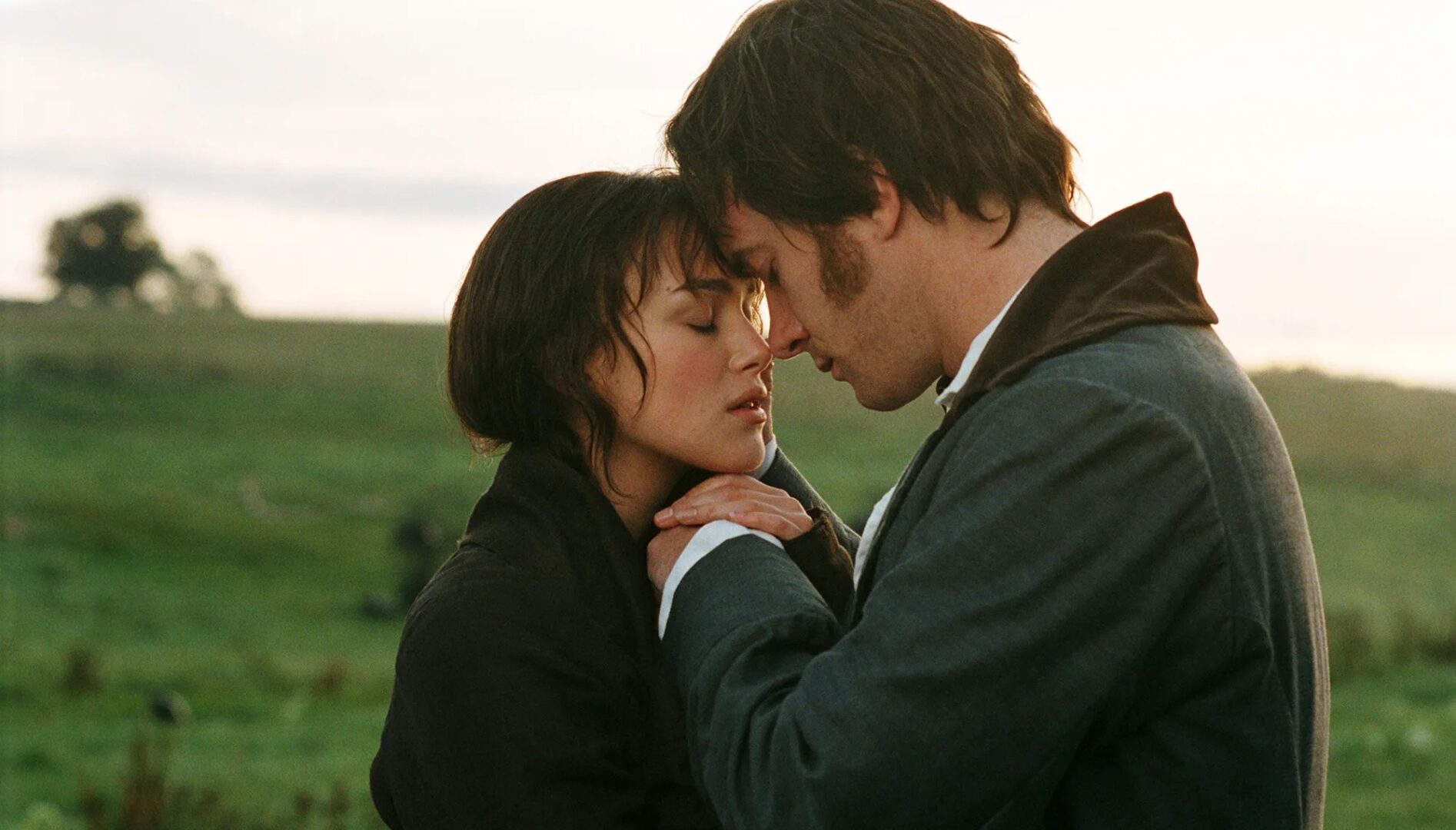 A photo of a man and a woman about to kiss in a landscape of lush grass and trees