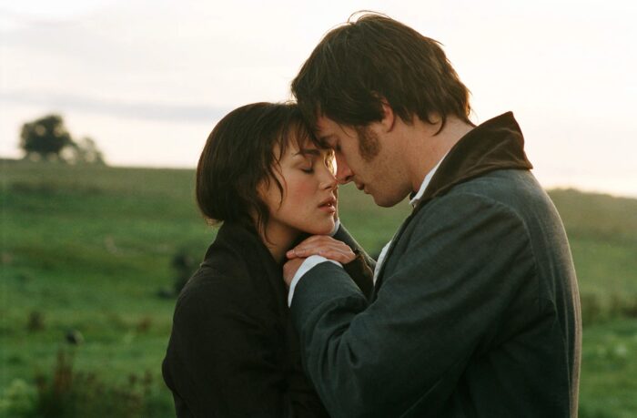 A photo of a man and a woman about to kiss in a landscape of lush grass and trees