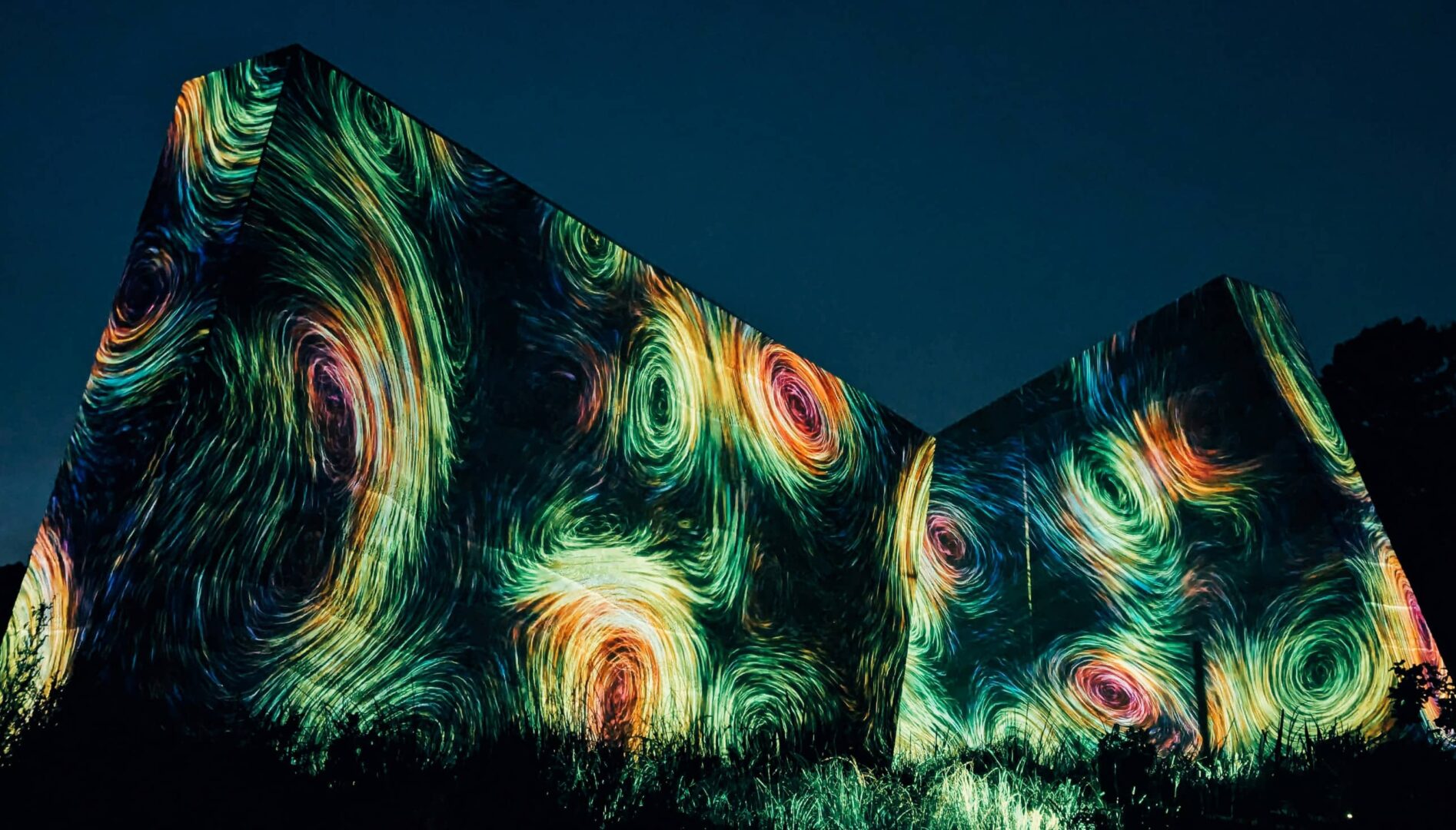 A dark wall at night with colorful, circular shapes projected upon it.