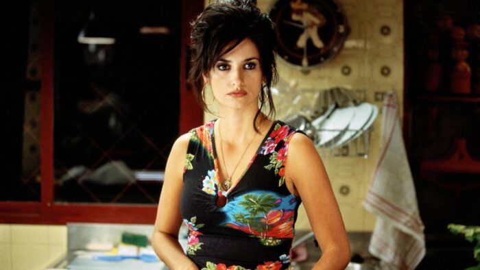A woman (Penelope Cruz) with a sleeveless flowered dress, a necklace, and black eyeliner on. Her dark hair is piled on top of her head.