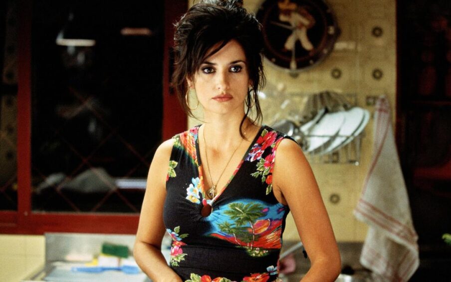 A woman (Penelope Cruz) with a sleeveless flowered dress, a necklace, and black eyeliner on. Her dark hair is piled on top of her head.