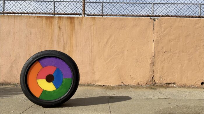 A photo of a color wheel on a sidewalk against a peach-colored wall