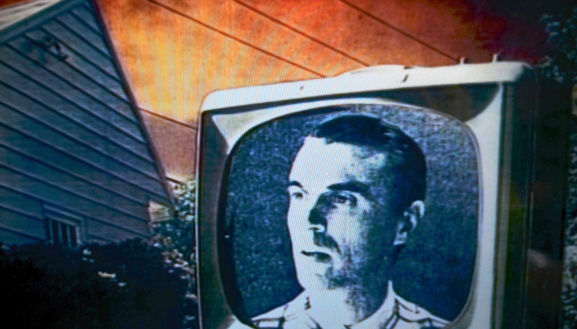 A music video film still with a black and white television with David Byrne's face on it