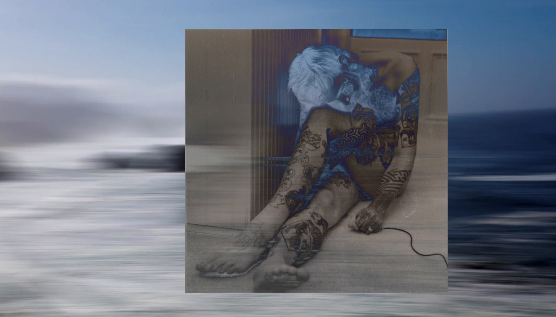 A black and white photograph of a person sitting on the floor, overlaid on a color photograph of the ocean.