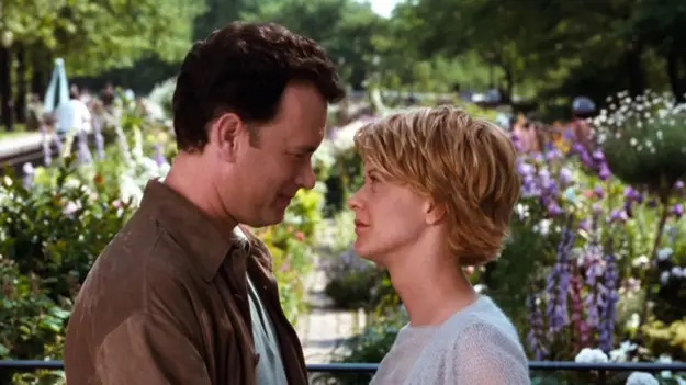 A man with short dark hair and a woman with short blond hair standing close and looking in each other's eyes