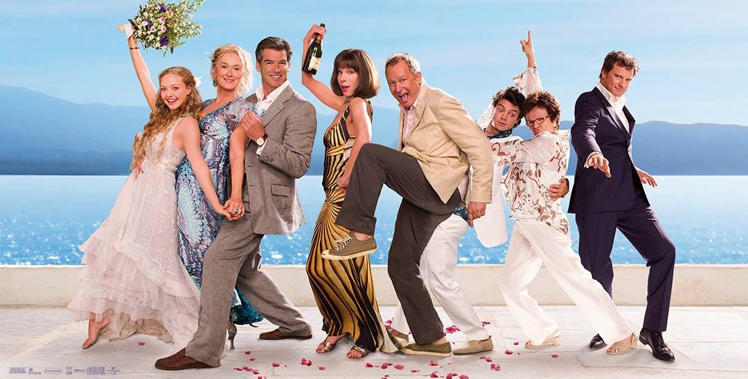 A group of people in fancy wedding attire standing in front of the ocean
