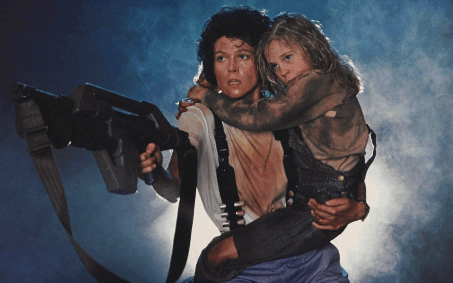 Film still of a woman holding a young girl on one arm and a large gun in the other hand