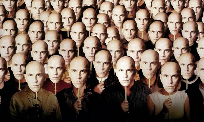 A group of people holding up John Malcovich masks over their faces.