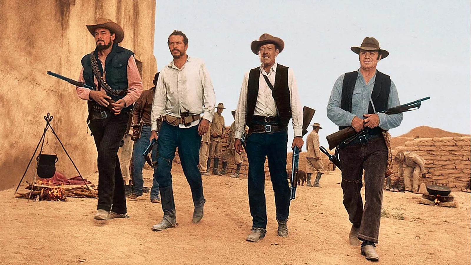 Four men in old "Western" outfits holding rifles.