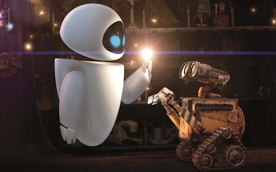 Animated film still of a futuristic looking white robot holding up a glowing light bulb in front of an older, work looking robot.