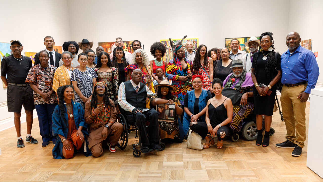 A group of people standing and sitting in a gallery.