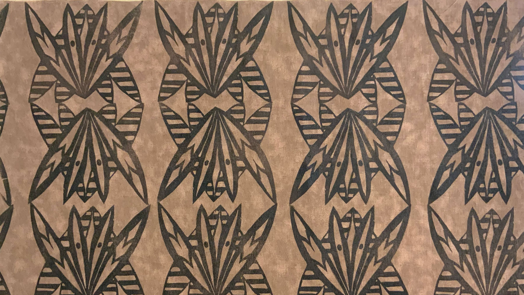 Image of a repeating black print on a light brown background.