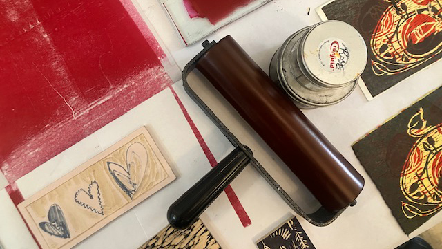 Printmaking supplies: red ink and a roller and printing plates