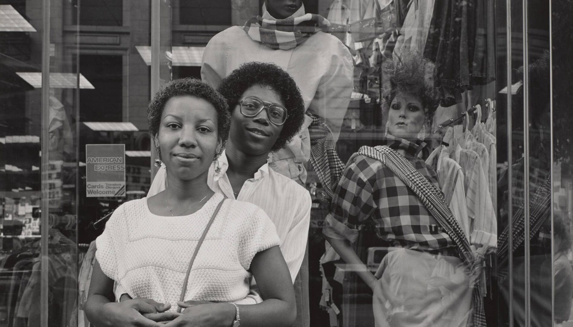 Black and white photograph of a couple standing in front of a shop window.