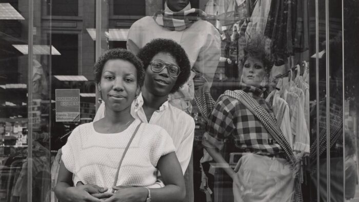 Black and white photograph of a couple standing in front of a shop window.
