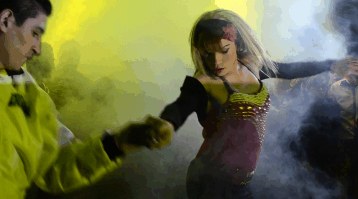 A woman and a man dancing on a dancefloor with smoke and yellow lights.
