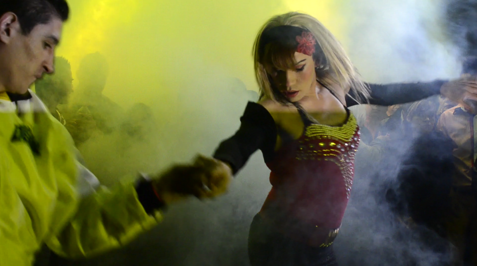 A woman and a man dancing on a dancefloor with smoke and yellow lights.