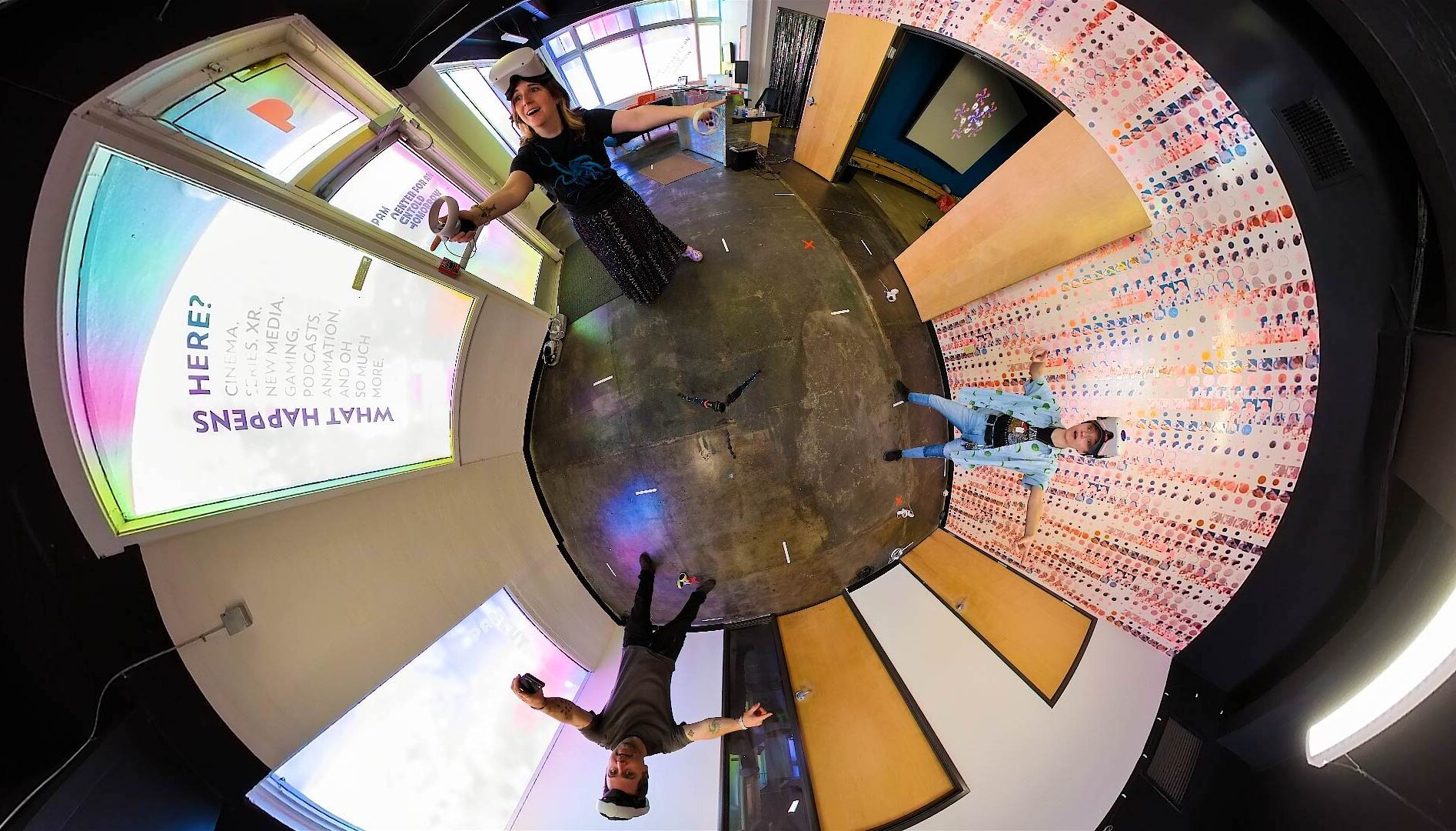 A fisheye photograph of three people in a room wearing virtual reality headsets.