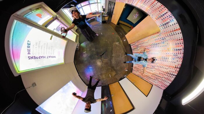 A fisheye photograph of three people in a room wearing virtual reality headsets.