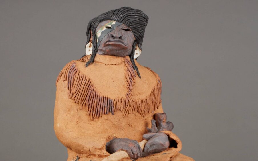 Clay and acrylic sculpture of a seated person.