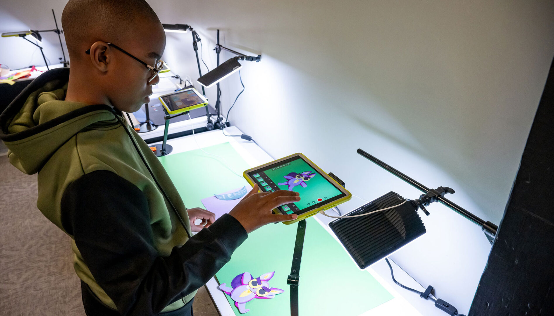 A boy with eyeglasses looking at an iPad mounted over a paper owl.