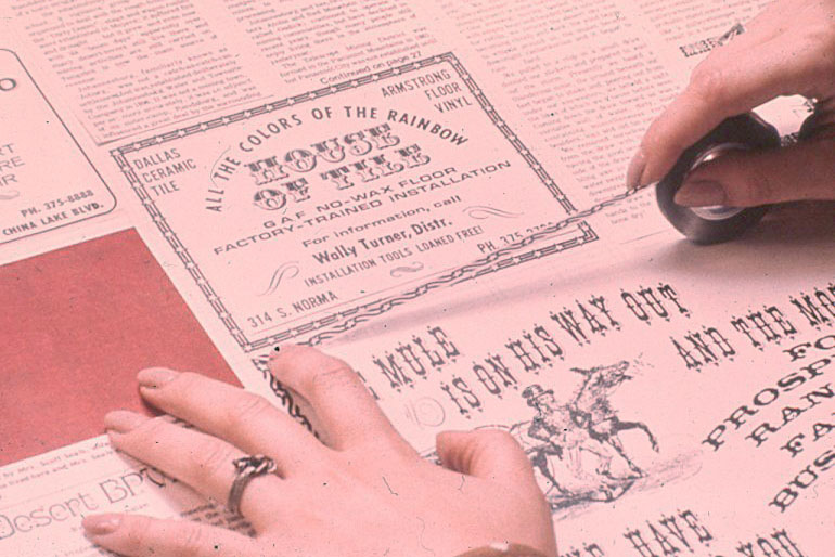 Vintage photo of someone laying out a newspaper by hand.