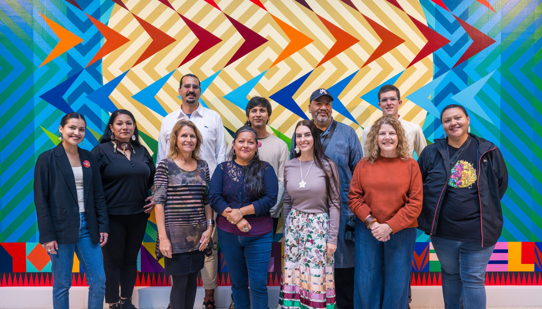 Photo of a group of people in front of Jeffrey Gibson's "BIRDS FLYING HIGH YOU KNOW HOW I FEEL"