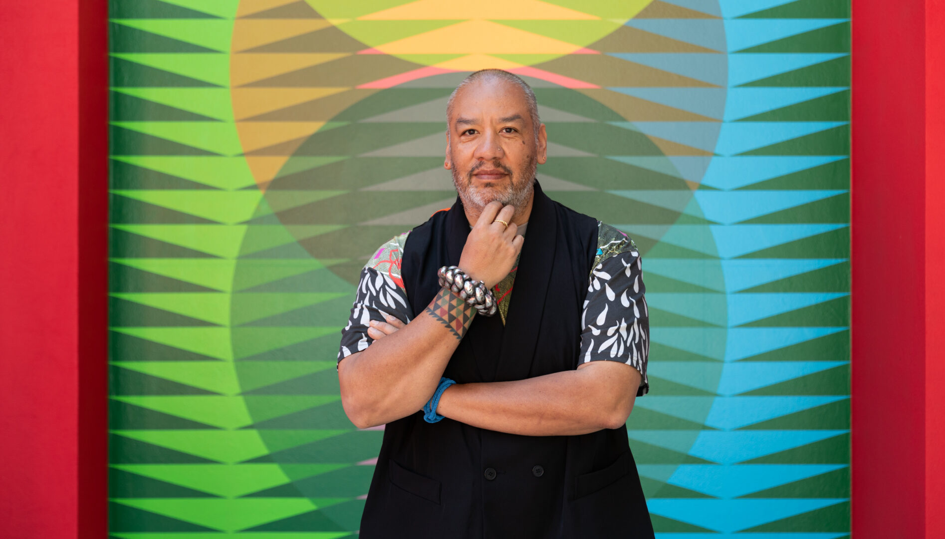 Portrait of artist Jeffrey Gibson in front of one of his artworks at the 2024 Venice Biennale.