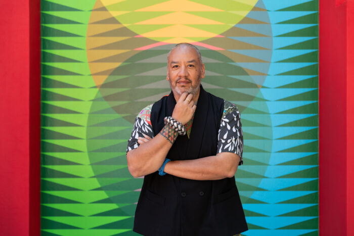 Portrait of artist Jeffrey Gibson in front of one of his artworks at the 2024 Venice Biennale.